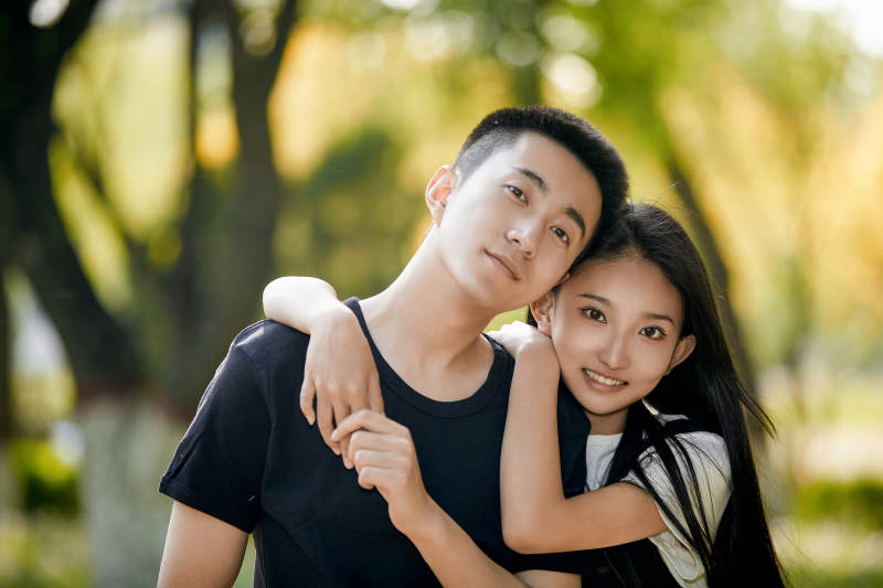 户外草坪上的恩爱年轻情侣