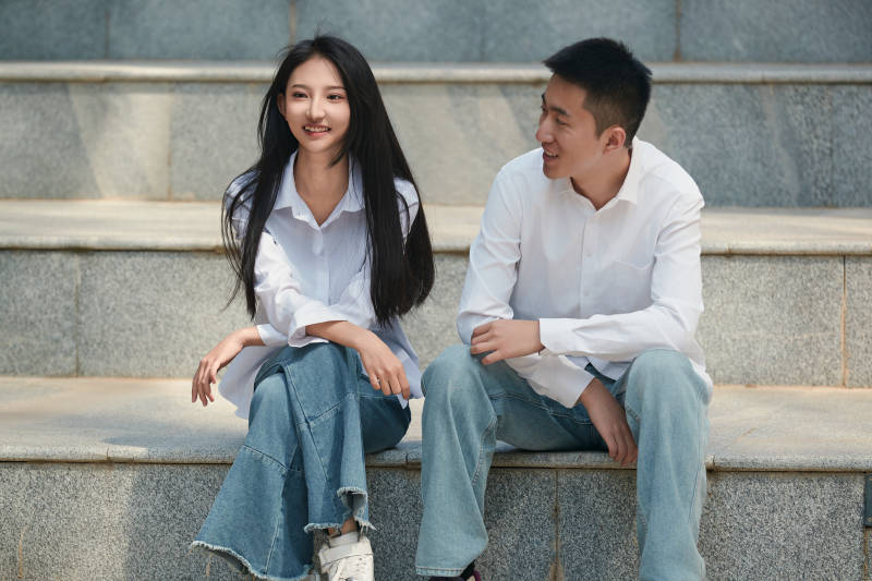 坐在户外台阶上的青年情侣