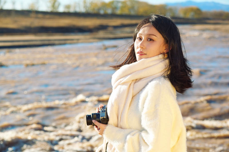 深秋户外手持相机的亚洲女性摄影师