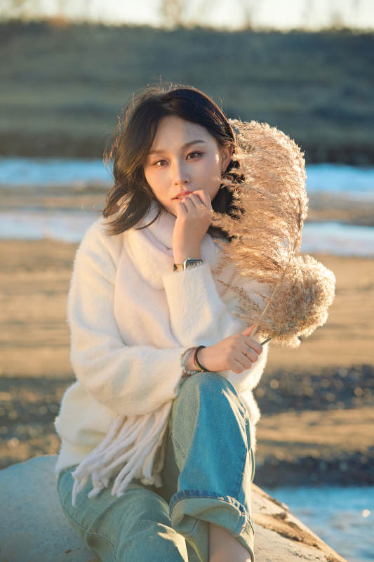 秋天在夕阳下的原野河边拍照的美女