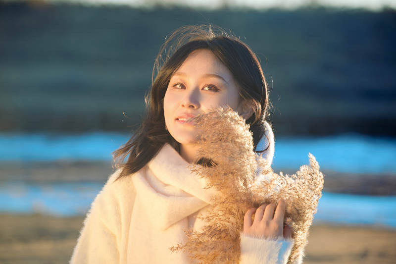 秋天在夕阳下的原野河边拍照的美女