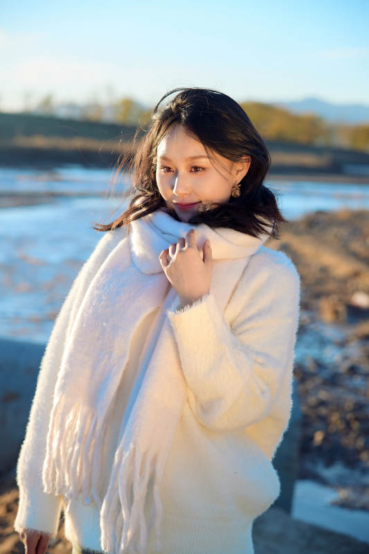 秋天在夕阳下的原野河边拍照的美女