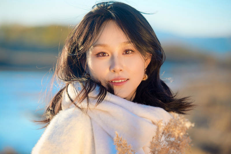 秋天在夕阳下的原野河边拍照的美女