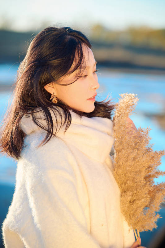 秋天在夕阳下的原野河边拍照的美女