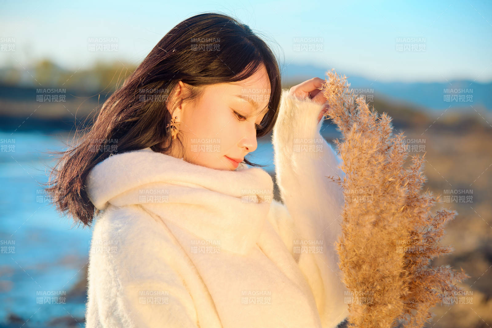 秋天在夕阳下的原野河边拍照的美女