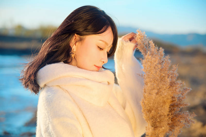 秋天在夕阳下的原野河边拍照的美女