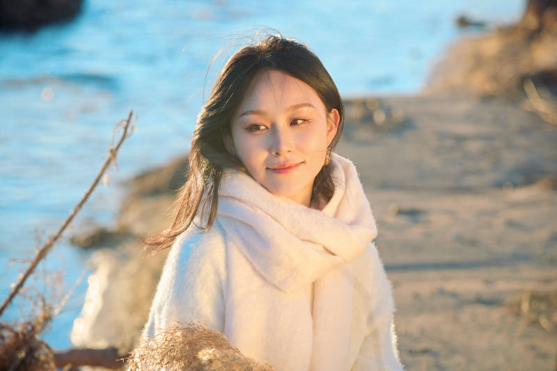 秋天在夕阳下的原野河边拍照的美女