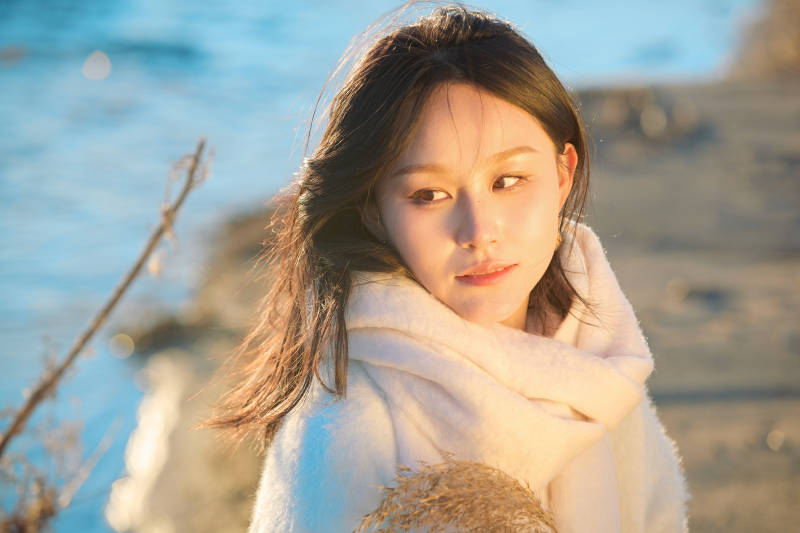 秋天在夕阳下的原野河边拍照的美女