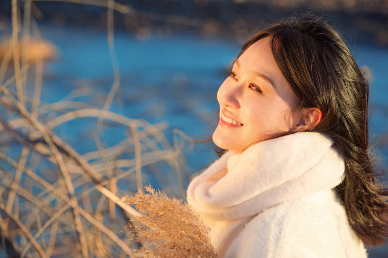 秋天在夕阳下的原野河边拍照的美女