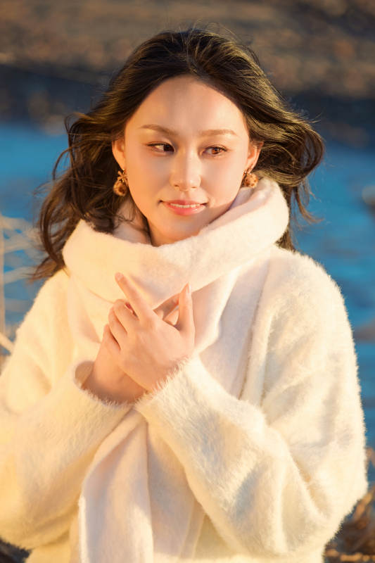 秋天在夕阳下的原野河边拍照的美女