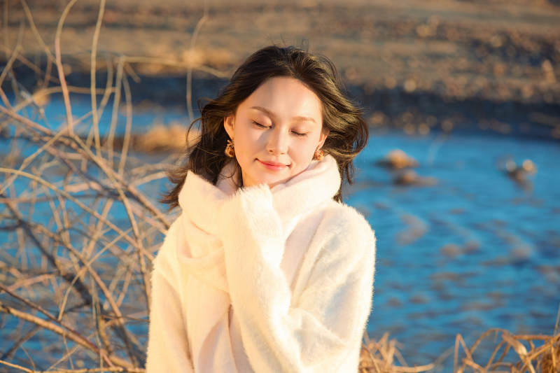 秋天在夕陽下的原野河邊拍照的美女