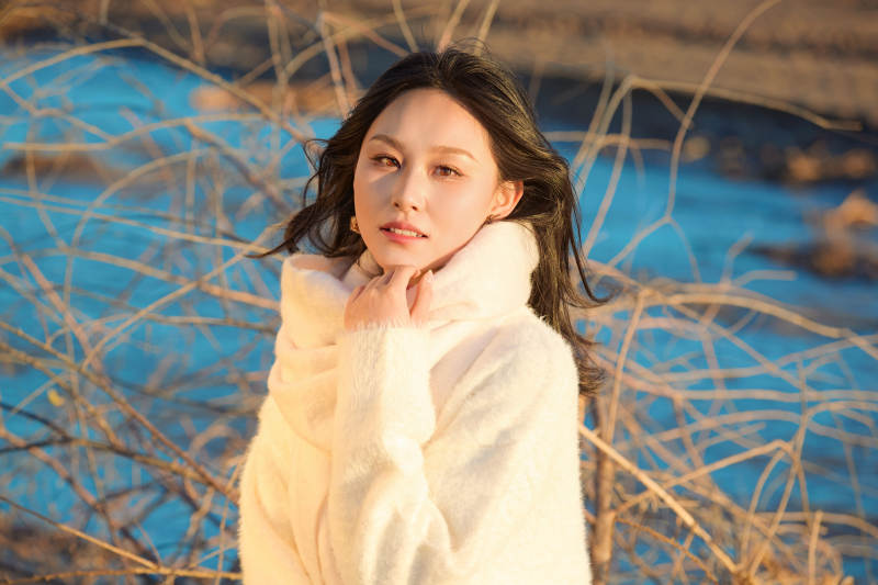 秋天在夕阳下的原野河边拍照的美女