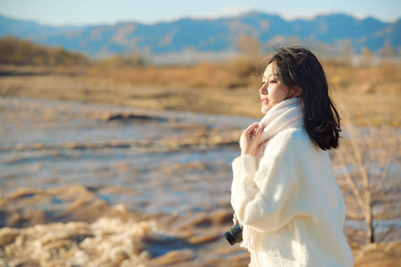 拿着相机的美女摄影师在深秋的户外拍摄