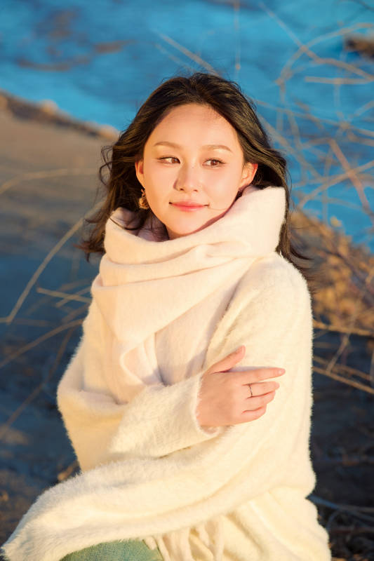 秋天在夕阳下的原野河边拍照的美女