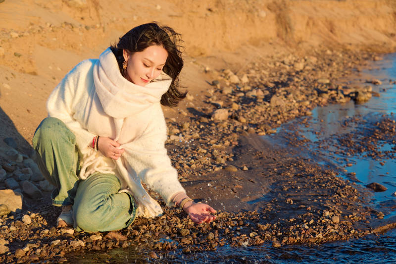 深秋夕阳下在户外河水边的东方女性