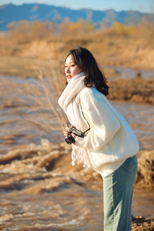 拿着相机的美女摄影师在深秋的户外拍摄