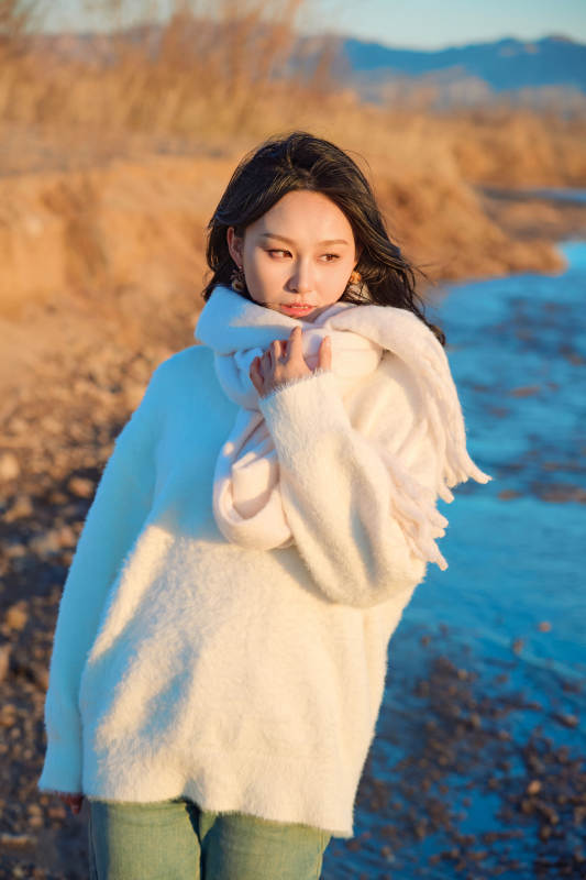 深秋夕阳下在户外河水边的东方女性