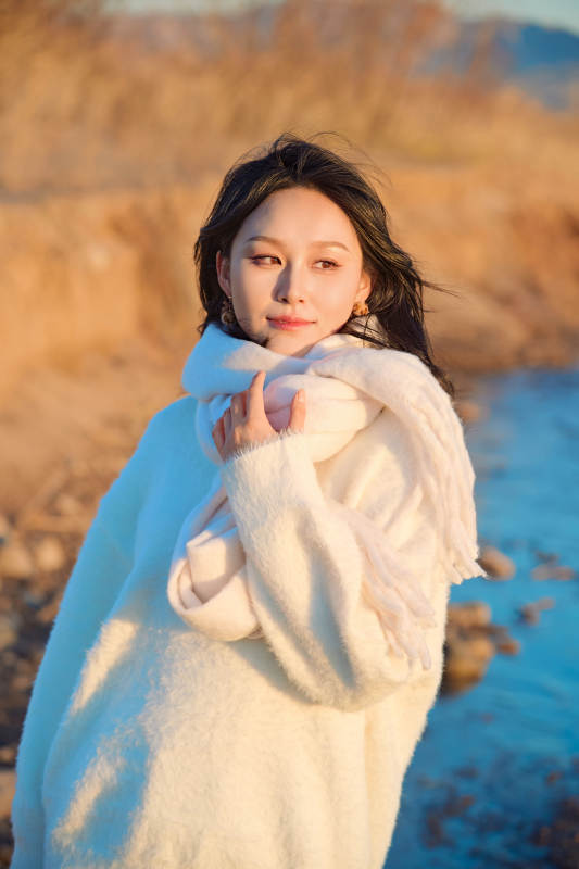 深秋夕阳下在户外河水边的东方女性