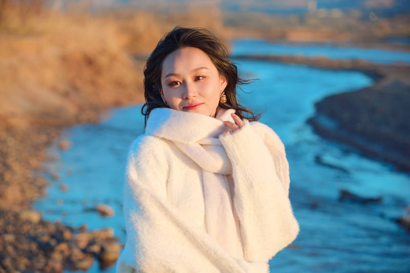 深秋夕阳下在户外河水边的东方女性