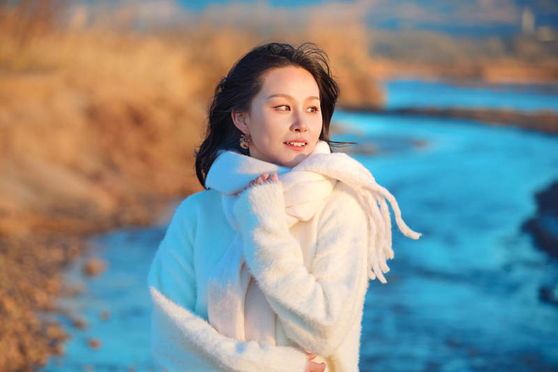 深秋夕阳下在户外河水边的东方女性