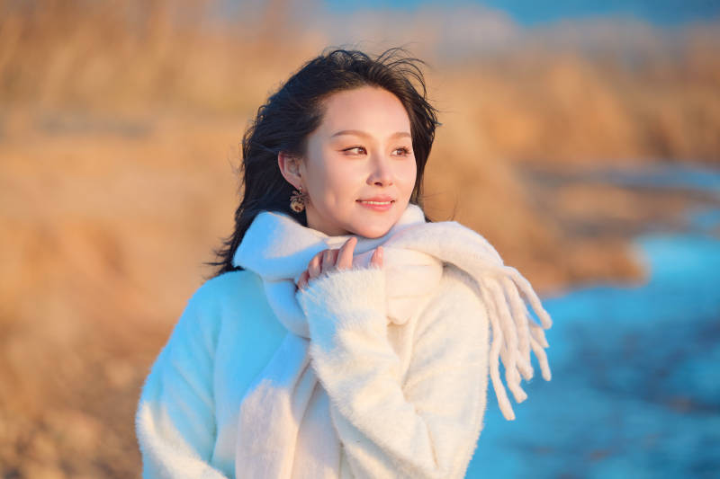 深秋夕阳下在户外河水边的东方女性