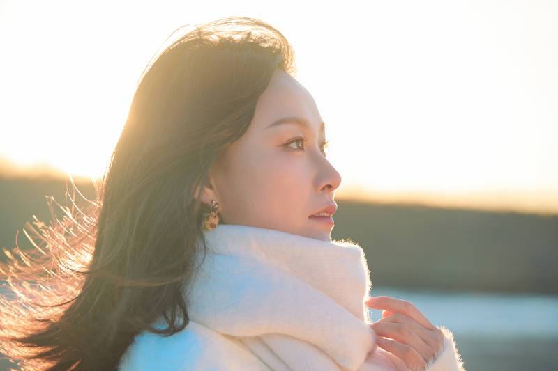 深秋夕阳下在户外河水边的东方女性