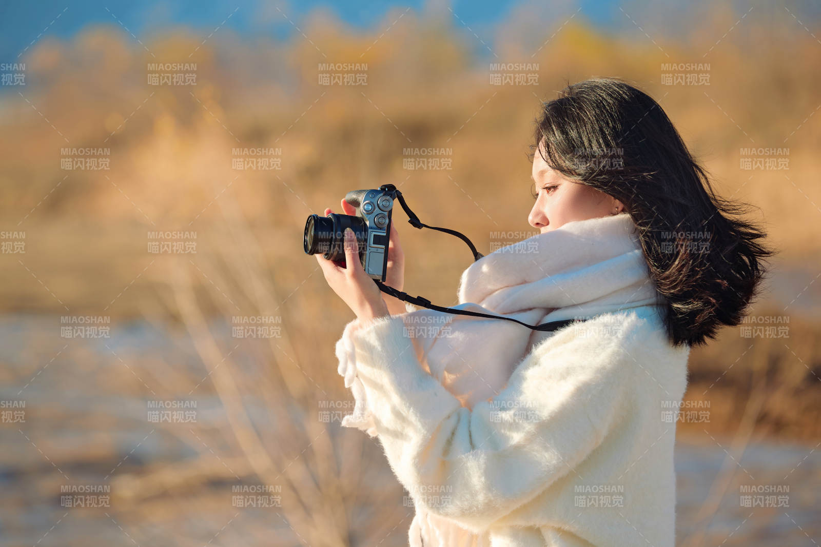 拿着相机的美女摄影师在深秋的户外拍摄图片