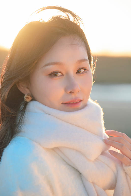 深秋夕阳下在户外河水边的东方女性