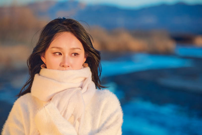 深秋夕阳下在户外河水边的东方女性