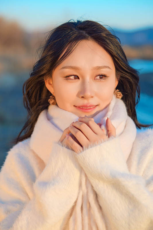 深秋夕阳下在户外河水边的东方女性