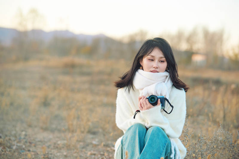 深秋户外手持相机的亚洲女性摄影师