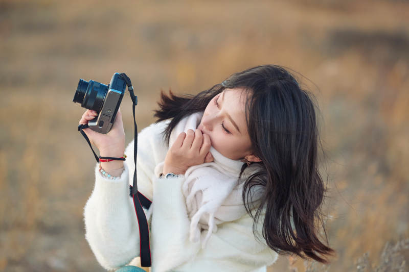 深秋户外手持相机的亚洲女性摄影师