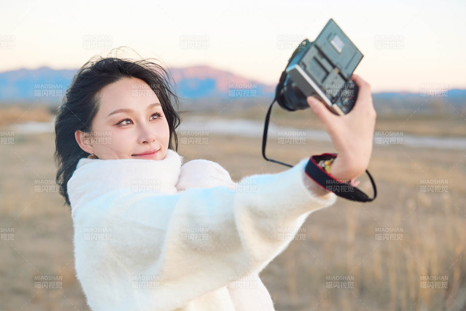 秋天夕陽下手持相機(jī)自拍的亞洲美女