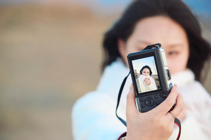秋天夕阳下手持相机自拍的亚洲美女
