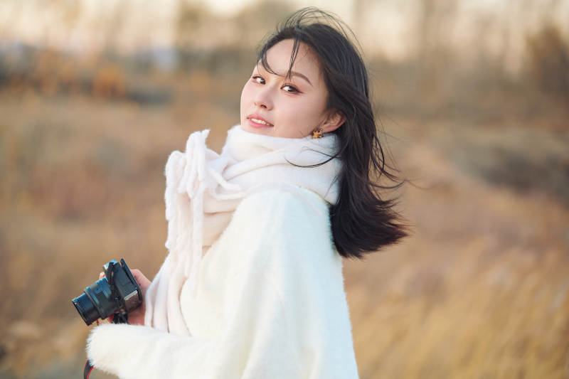 秋天夕阳下手持相机自拍的亚洲美女