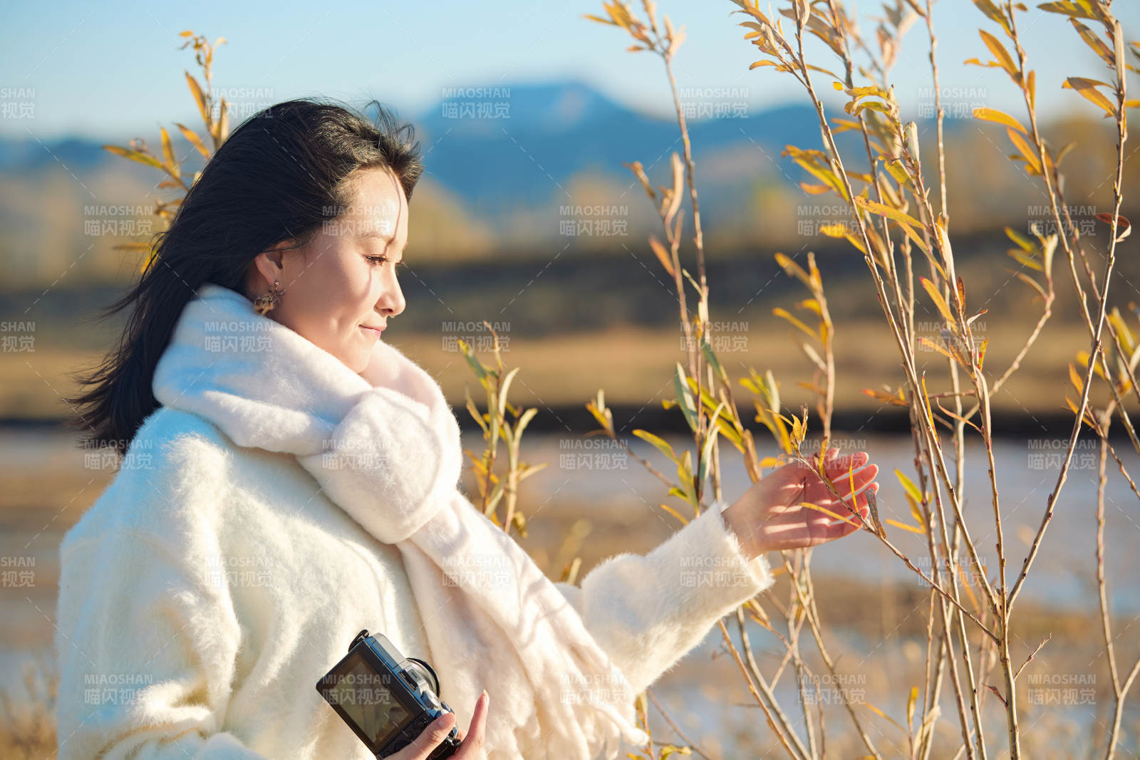 拿着相机的美女摄影师在深秋的户外拍摄