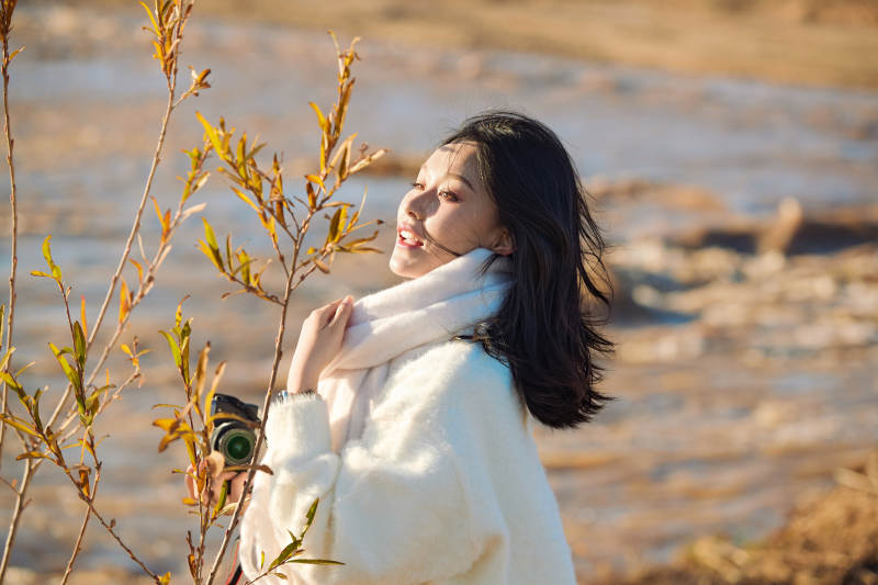 拿着相机的美女摄影师在深秋的户外拍摄