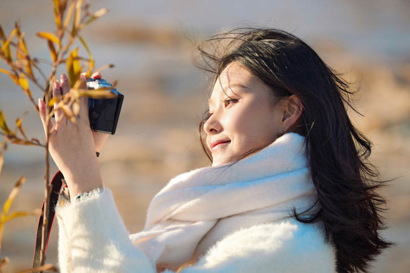拿着相机的美女摄影师在深秋的户外拍摄