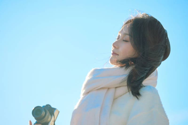 拿着相机的美女摄影师在深秋的户外拍摄