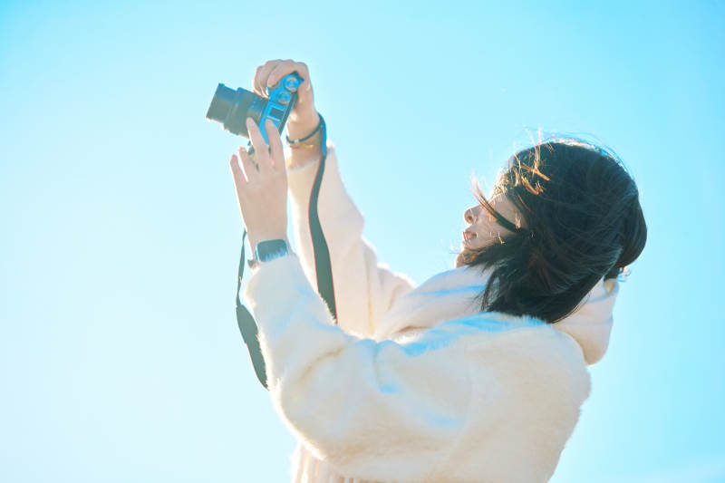 拿着相机的美女摄影师在深秋的户外拍摄