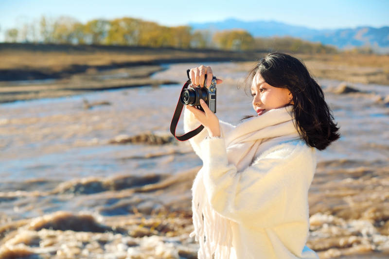 深秋户外手持相机的亚洲女性摄影师