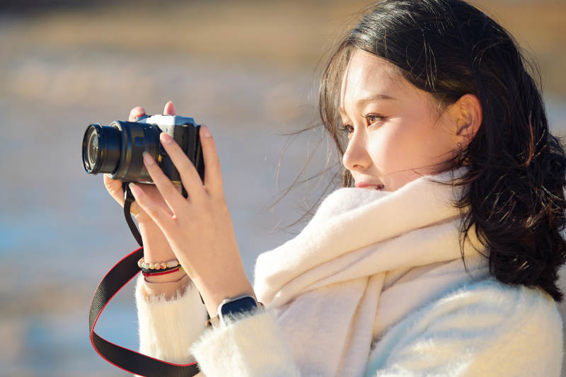 深秋户外手持相机的亚洲女性摄影师