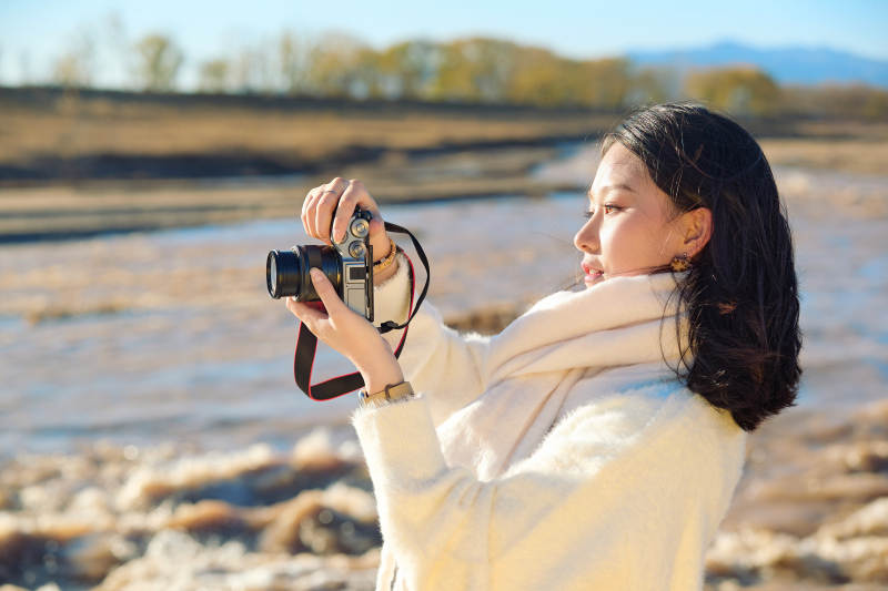 深秋户外手持相机的亚洲女性摄影师
