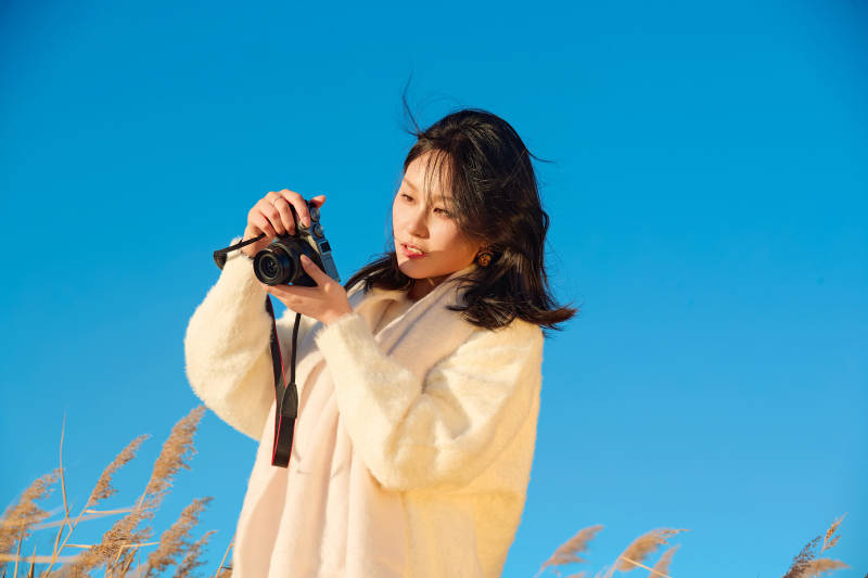 秋天晴朗的午后在芦苇荡里拍照的女性摄影师