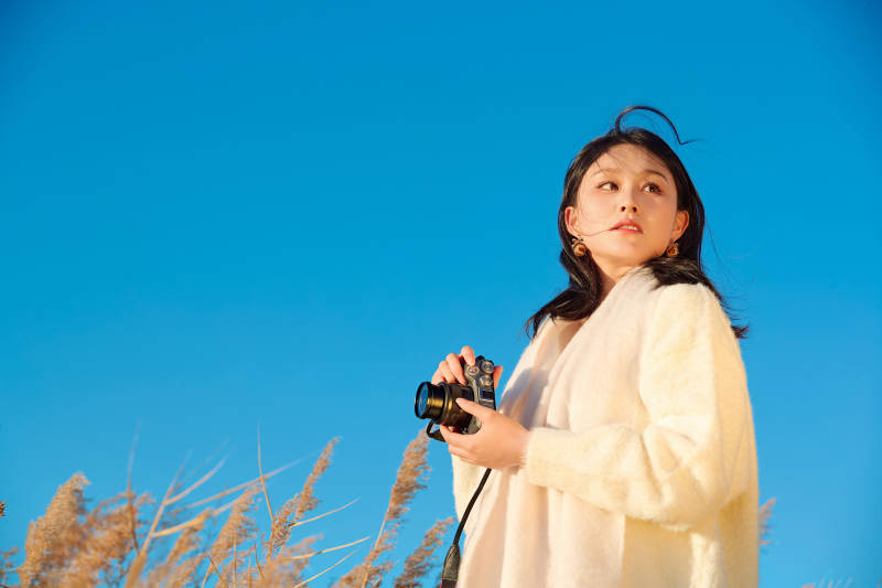 秋天晴朗的午后在芦苇荡里拍照的女性摄影师