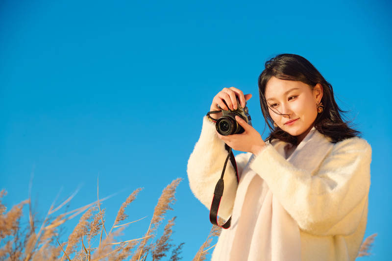 秋天晴朗的午后在芦苇荡里拍照的女性摄影师