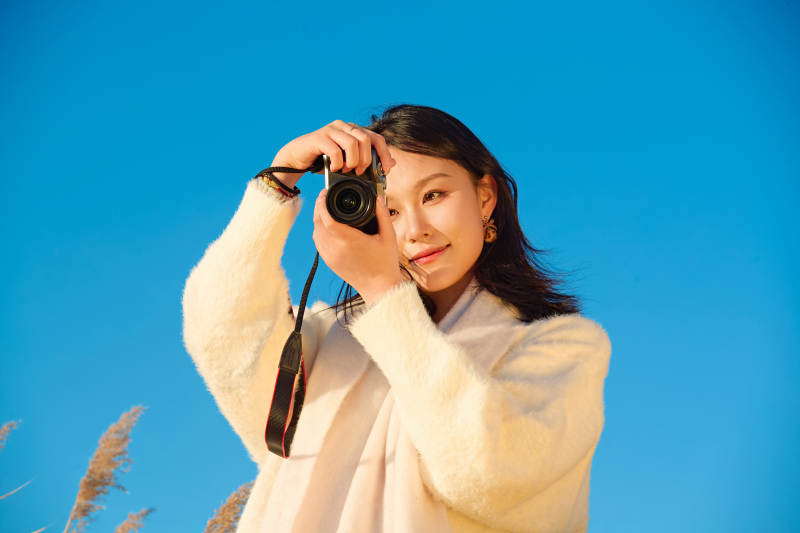 秋天晴朗的午后在芦苇荡里拍照的女性摄影师