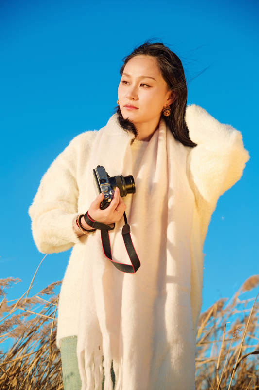 秋天晴朗的午后在芦苇荡里拍照的女性摄影师