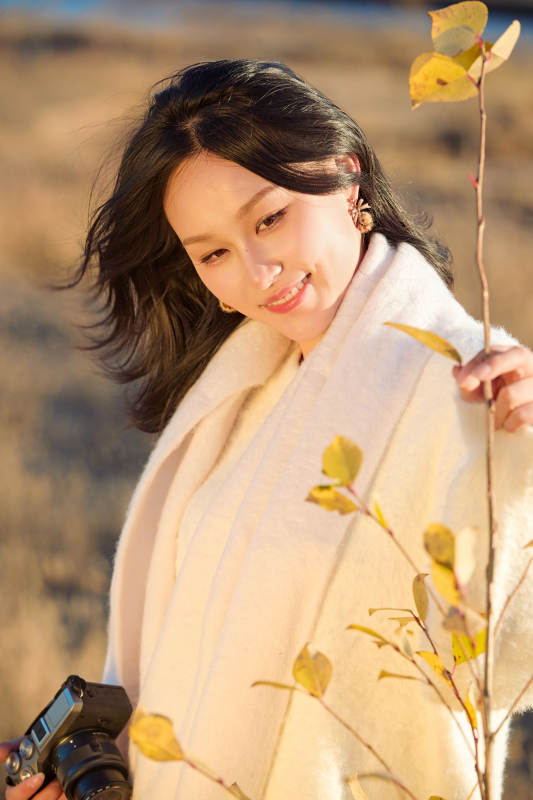 秋天晴朗的午后在芦苇荡里拍照的女性摄影师