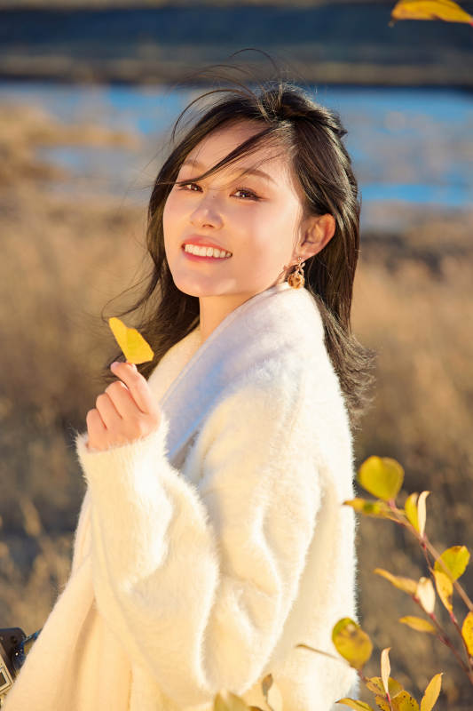 秋天晴朗的午后在芦苇荡里拍照的女性摄影师